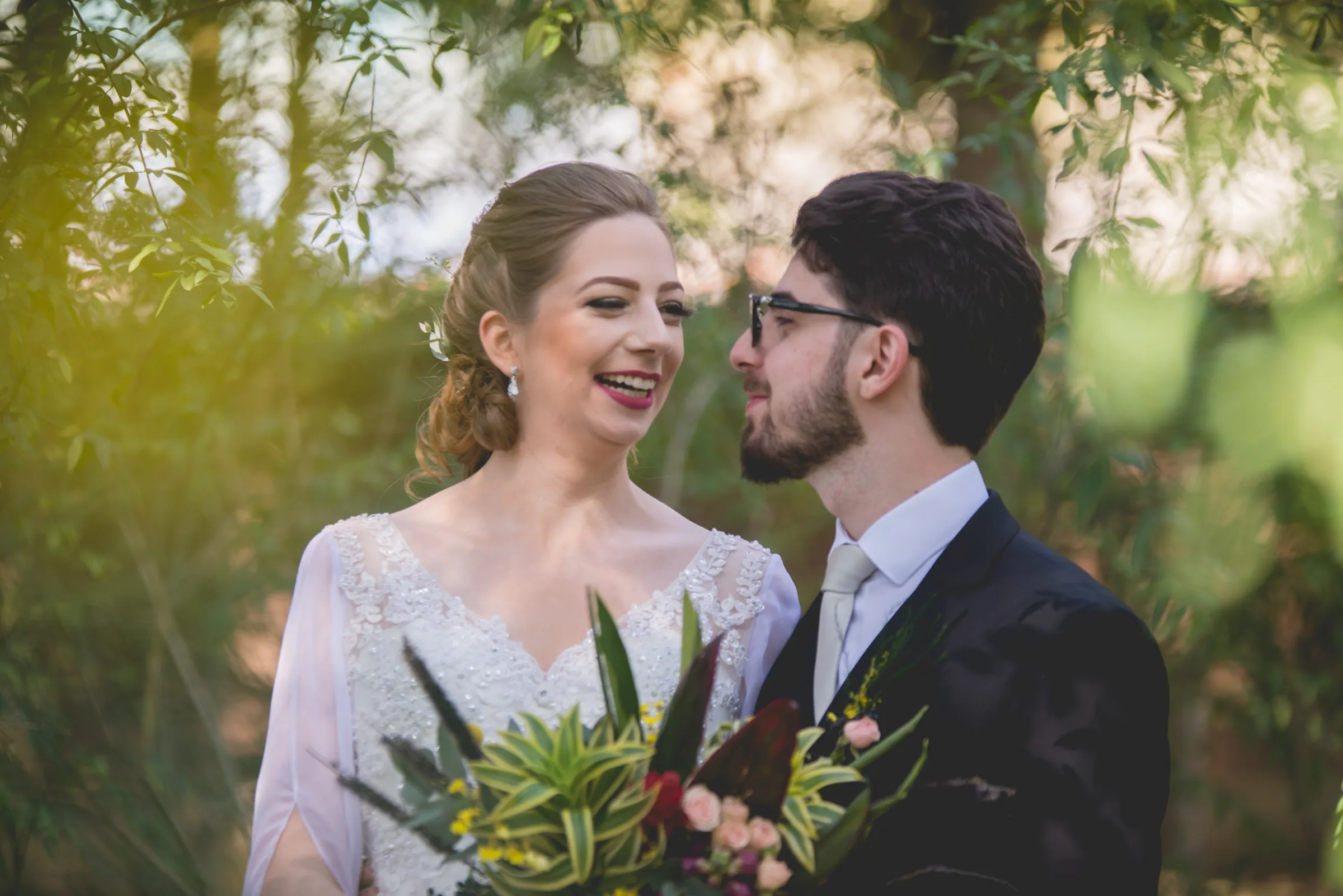 Casal trocando olhares sob folhagens iluminadas pelo sol da tarde