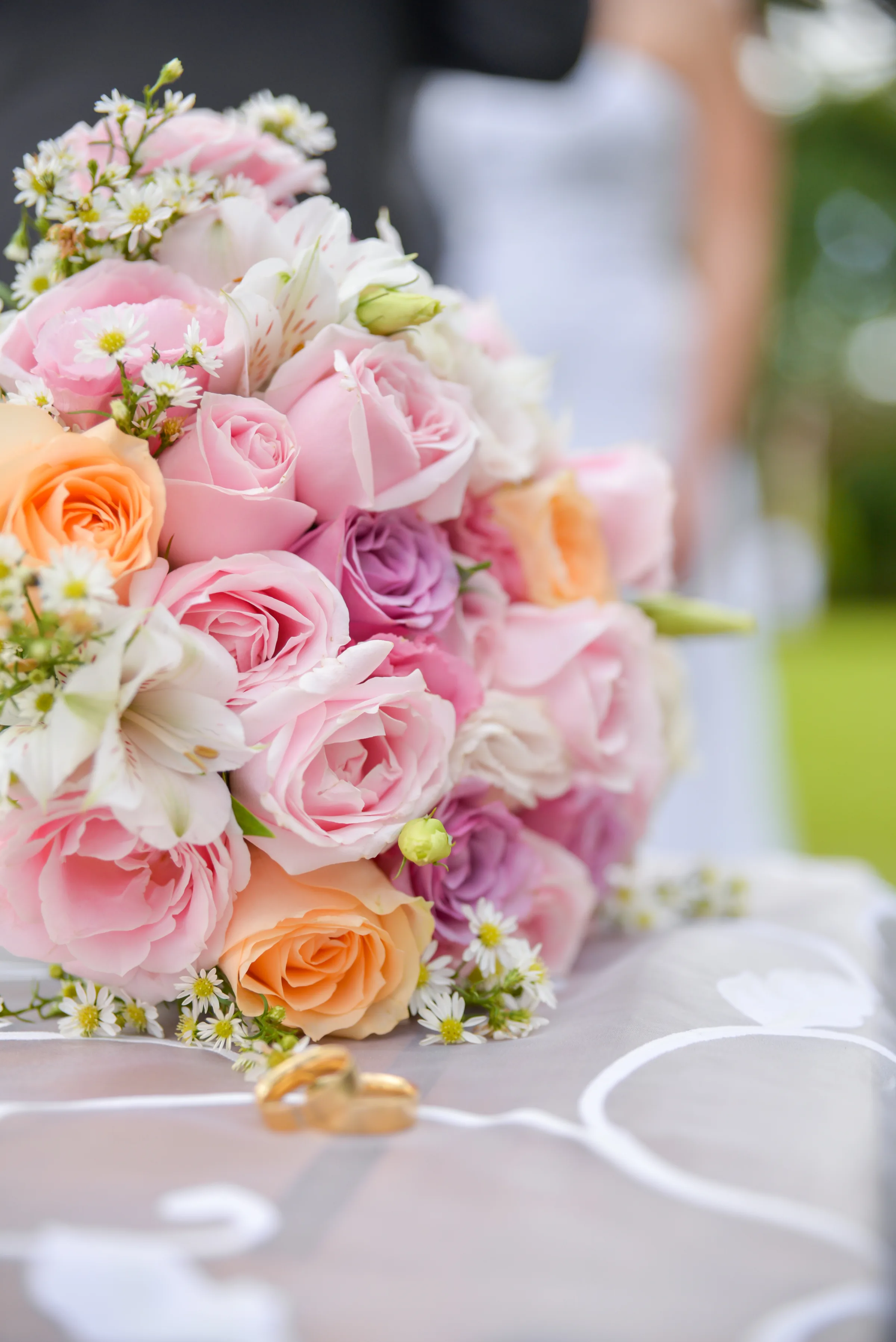 Buquê de rosas rosadas e alianças douradas sobre tecido claro
