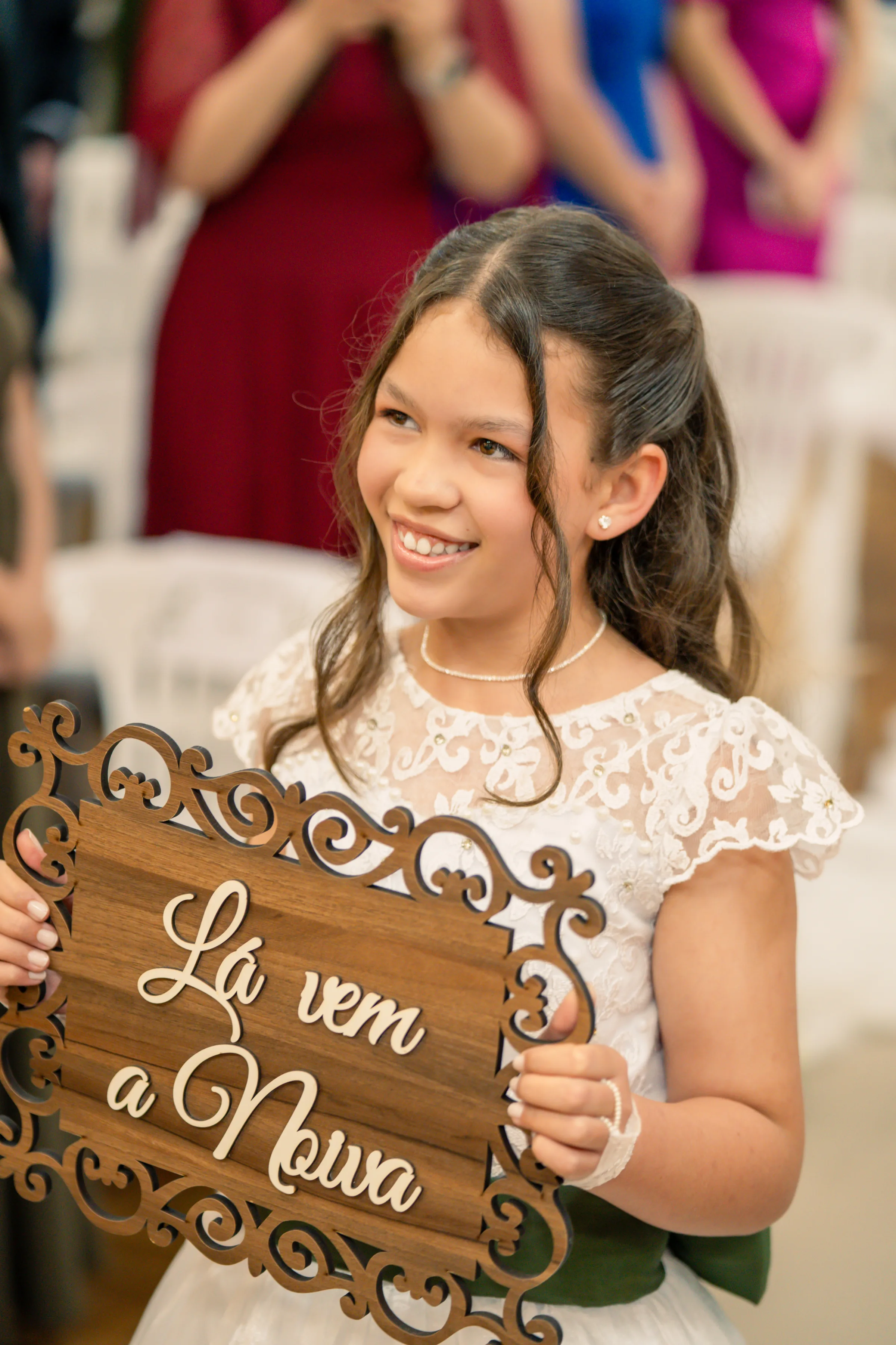 Menina sorrindo com placa de madeira escrita Lá vem a noiva