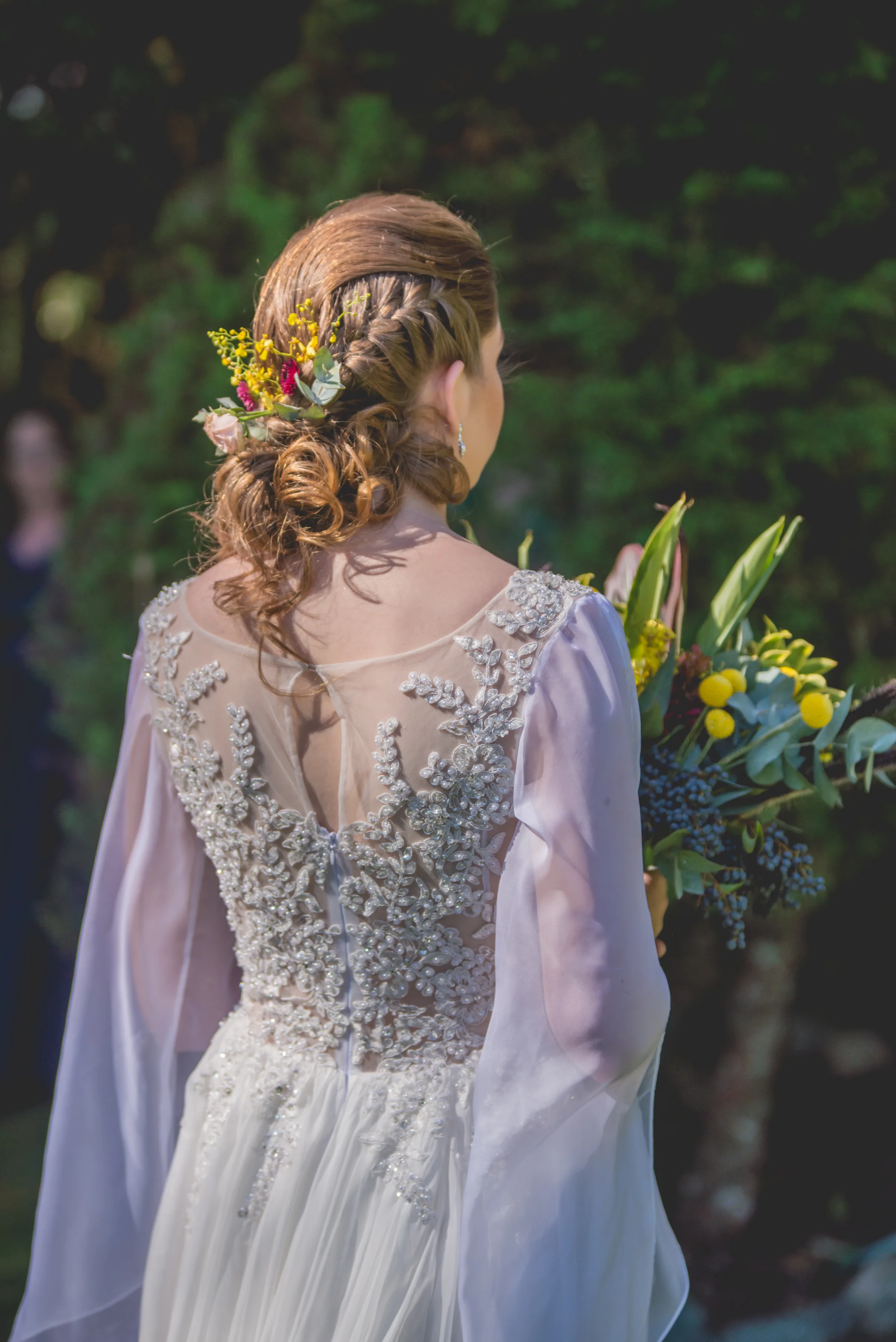 Costas do vestido rendado e coque com flores amarelas no cabelo