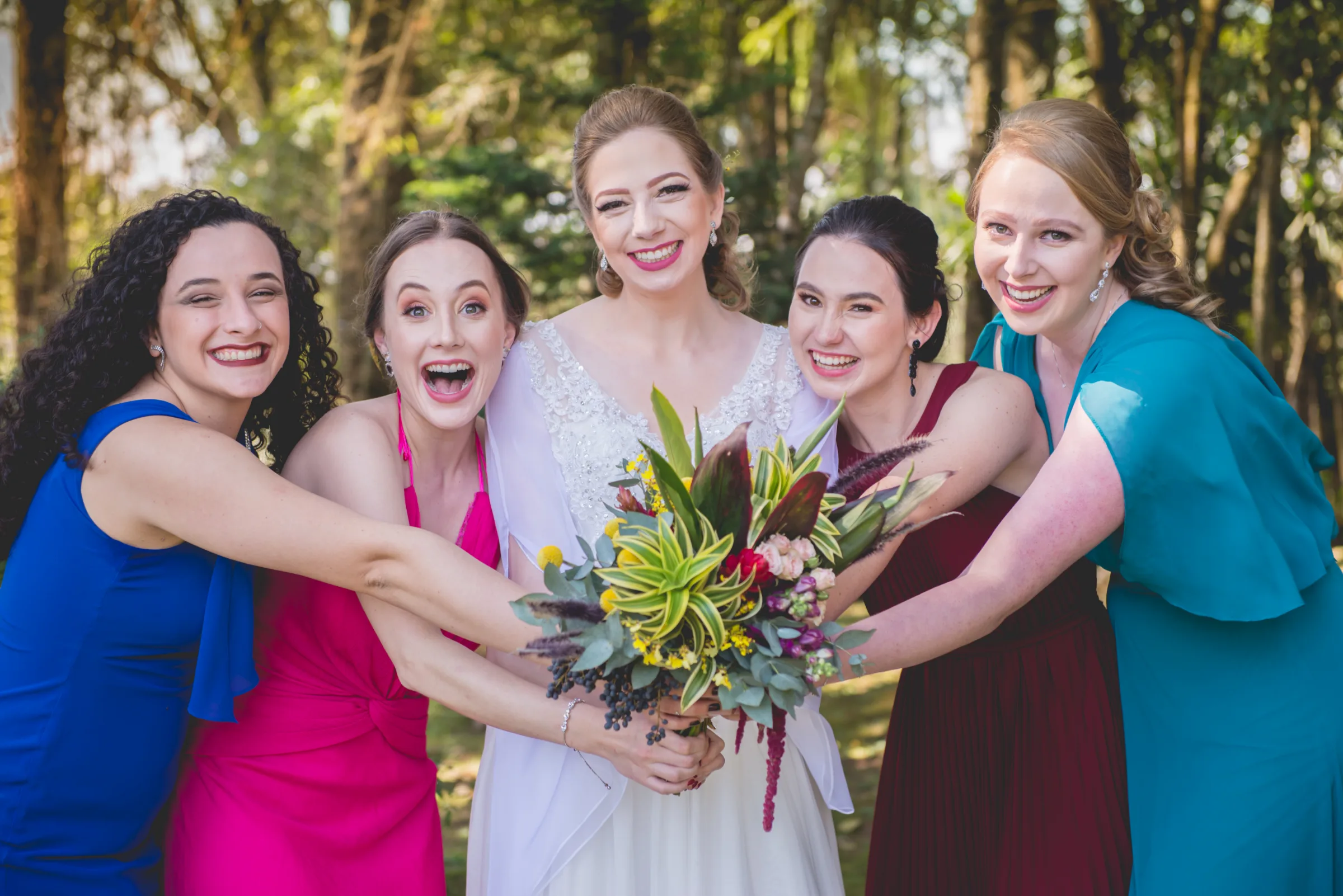 Noiva e quatro amigas em vestidos coloridos segurando o buquê, rindo