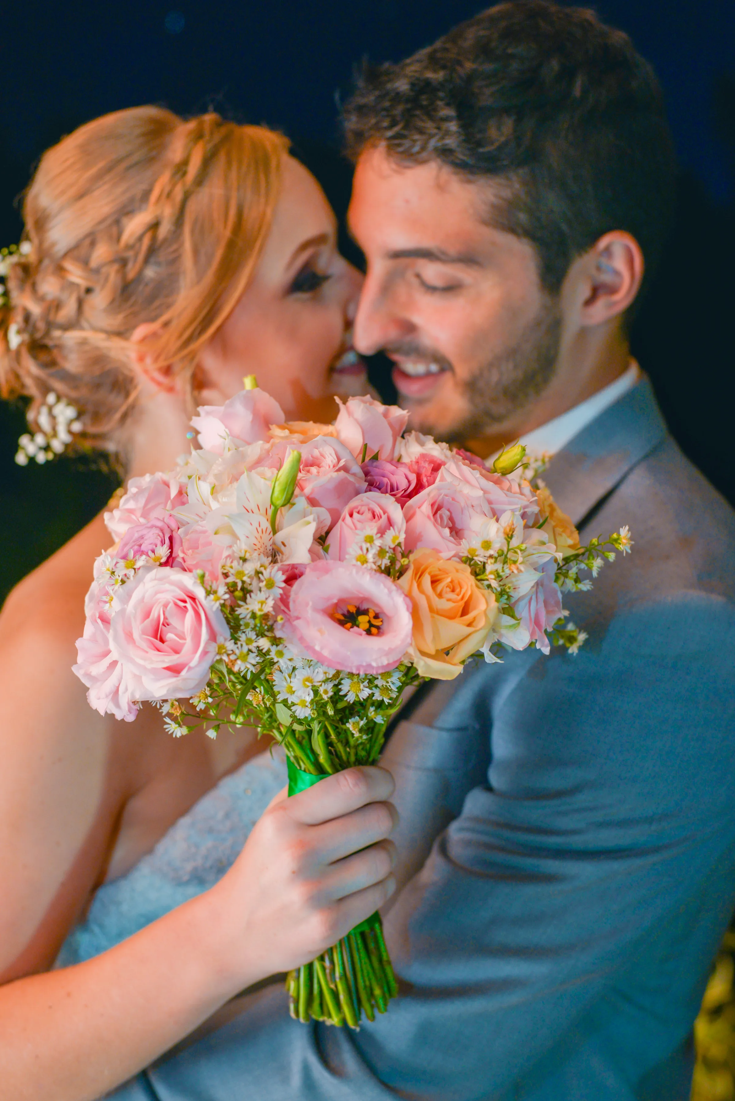 Buquê de rosas claras em foco diante do casal quase se beijando à noite